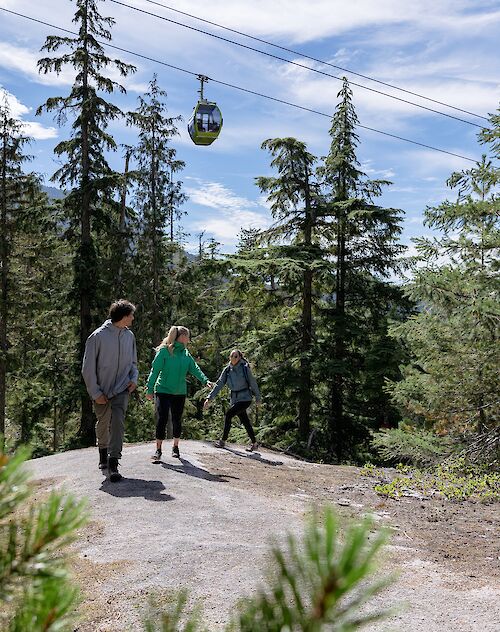 Three people waking with a gondola in the background