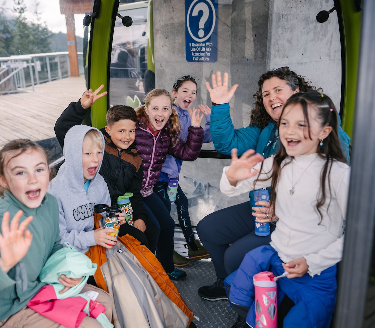 A group of students waving in a gondola cabin