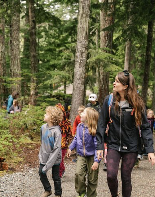 A teacher and students walking in the forest