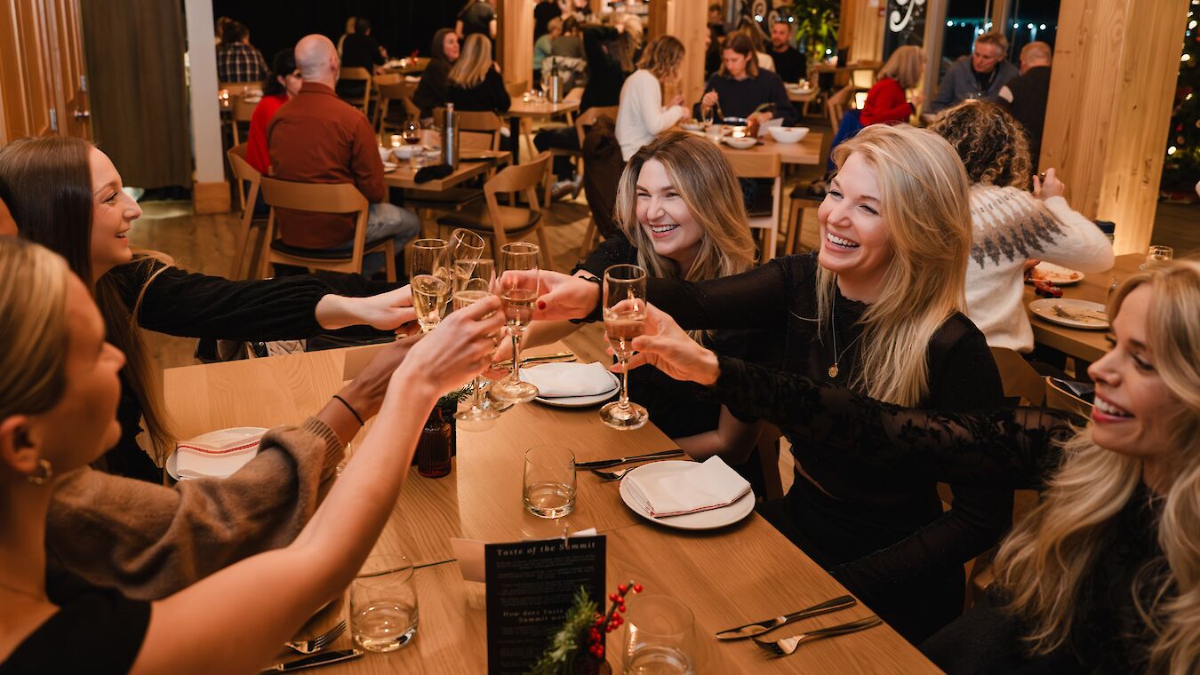 Colleagues raising their glasses during a festive dinner at the Sea to Sky Gondola Summit Lodge.