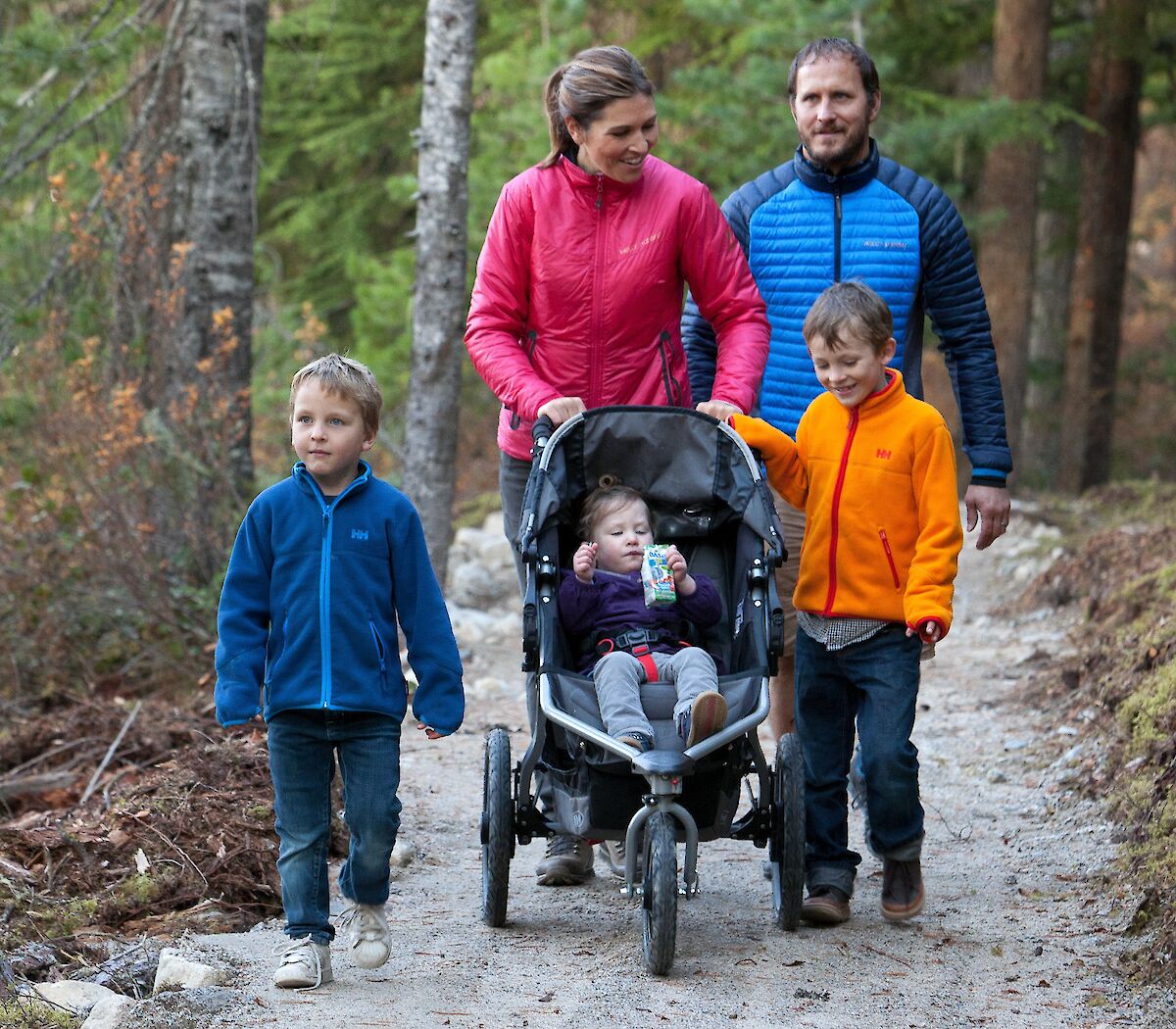 A family walking on a trail with a stroller
