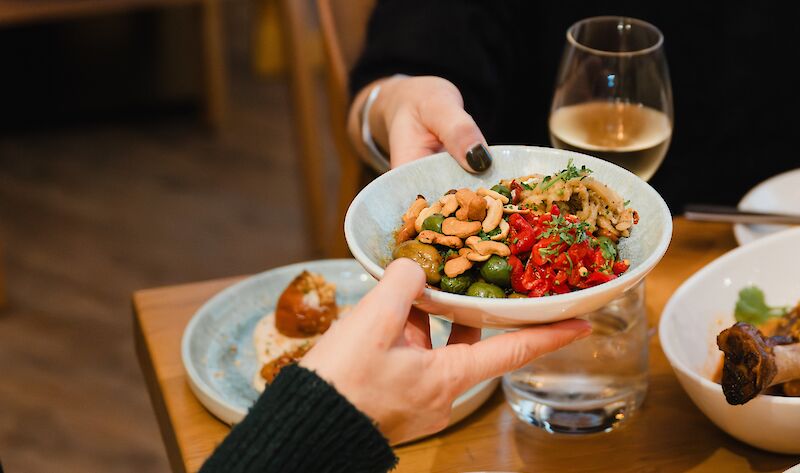 someone passing a bowl of olives