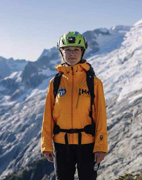 a lady standing with a mountain view behind
