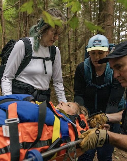 three people holding a lady on a stretcher