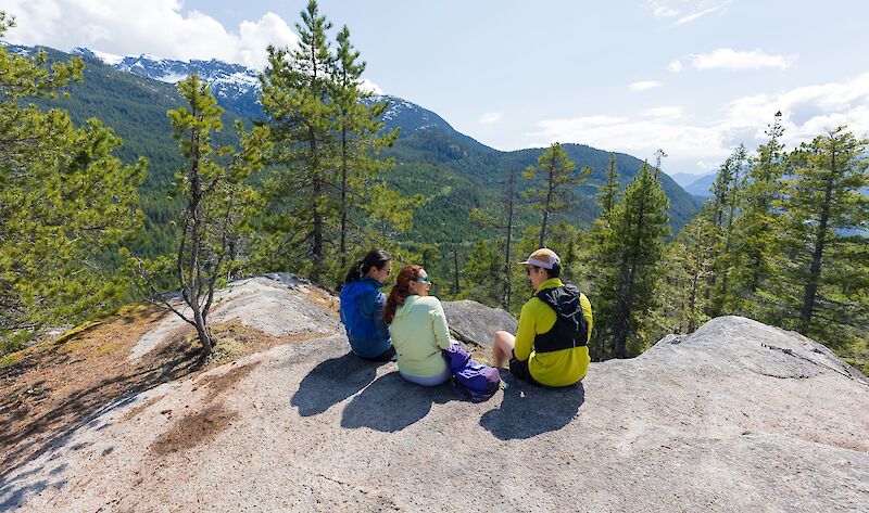 Three people sitting on a rock
