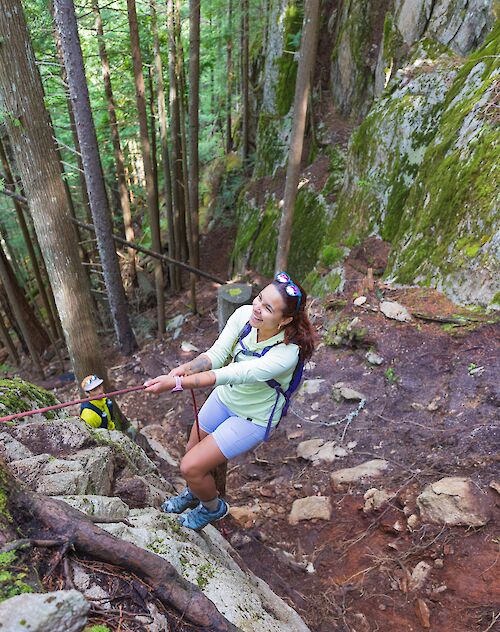 a hiker on a trail using a rope