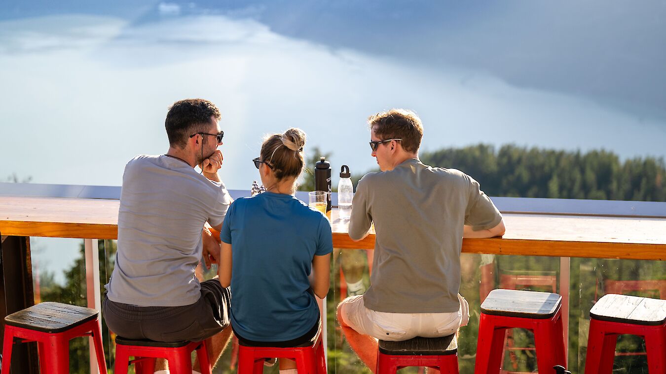three people sitting at a table looking at the ocean view