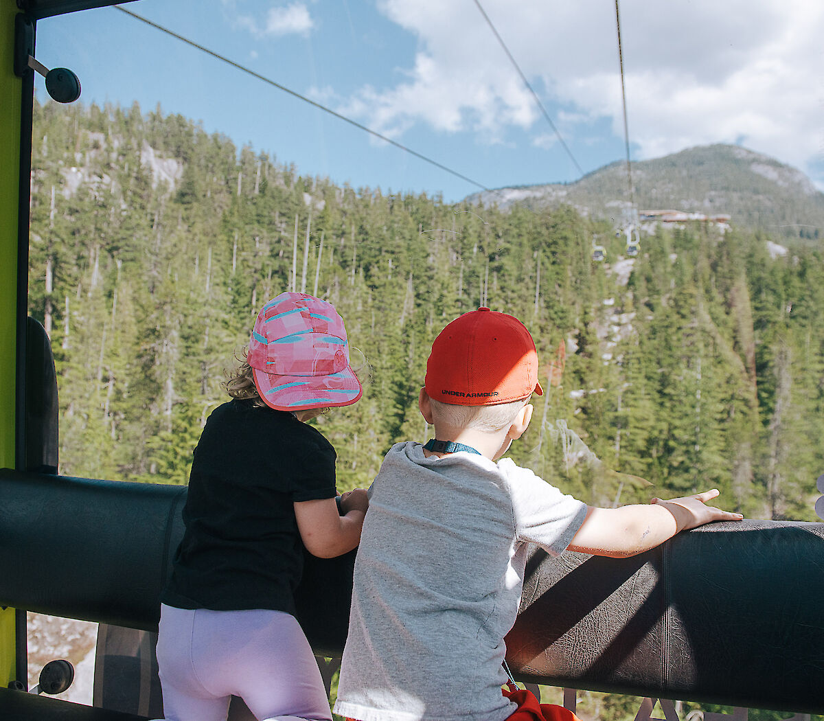 two children looking out the gondola window at the summit