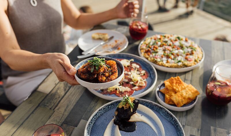 a lady holding a plate of food surrounded by other food