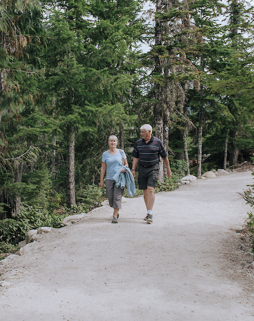 an elderly man and women walking on a trail