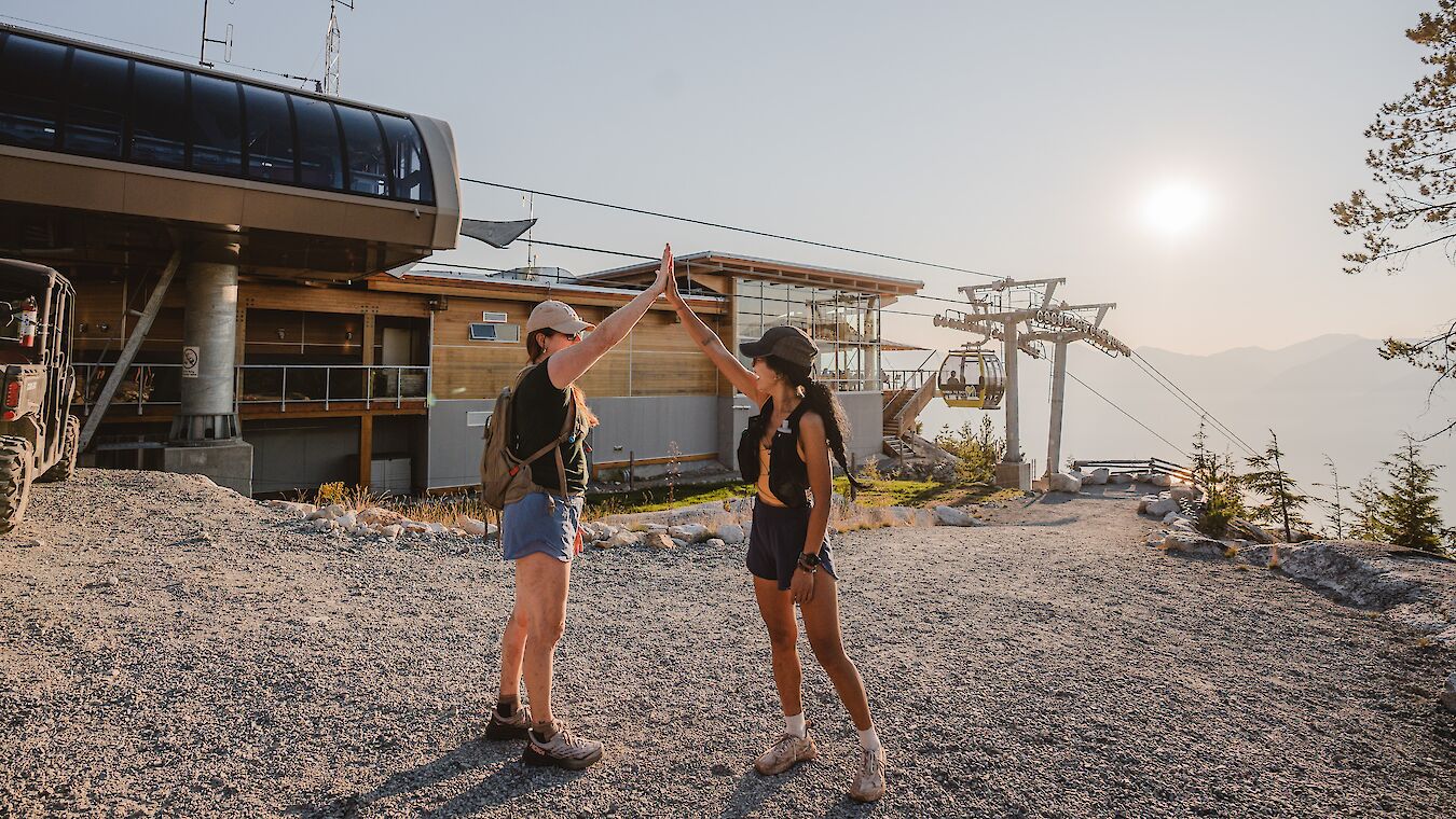 two women high fiving at the summit