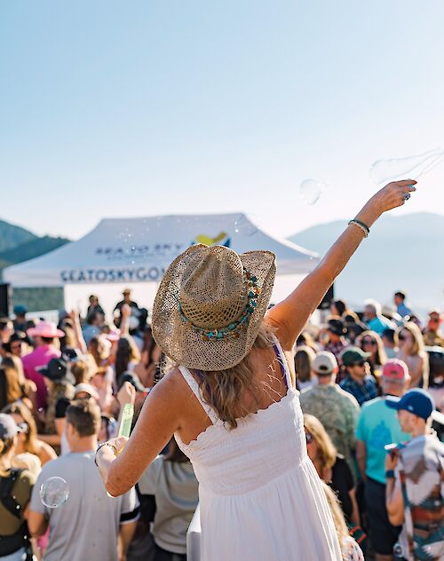 a women using a bubble maker in front of a crowd at mountain music