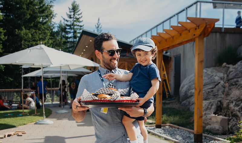 a father and son walking with a tray of burgers