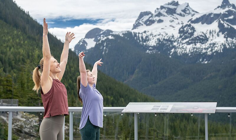 two women doing yoga with sky pilot in the background