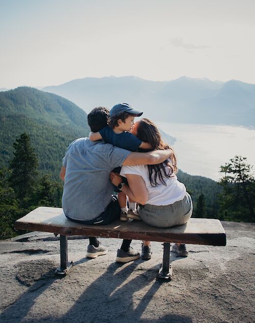 a family sitting on a bench looking at the view