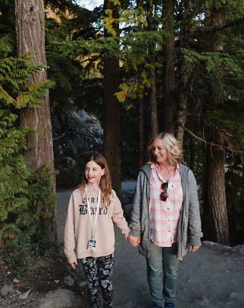 a mom and daughter walking on a trail