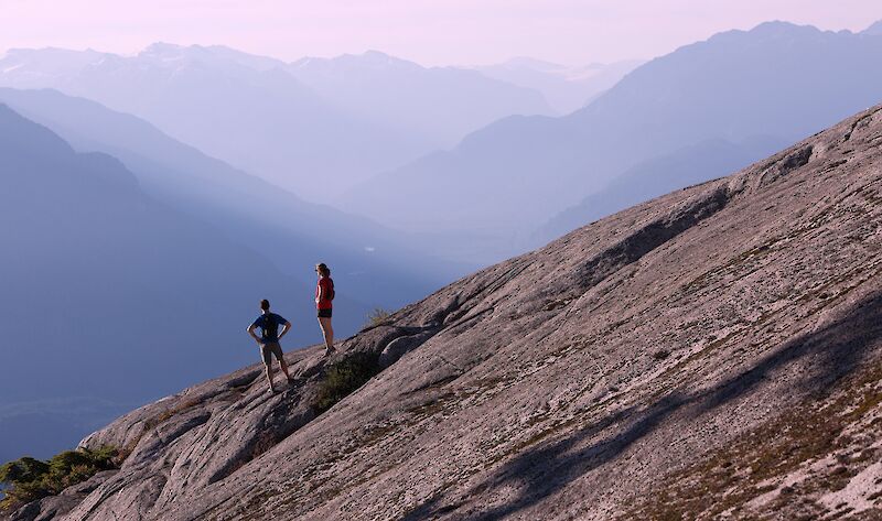 two people standing on a rock with mountain views in the distance