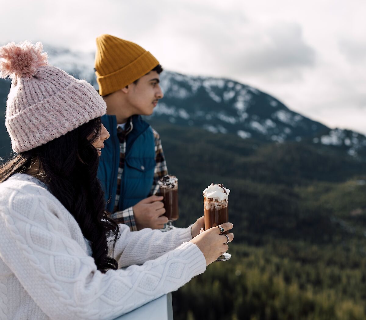 two people enjoying hot chocolate and looking out at the view